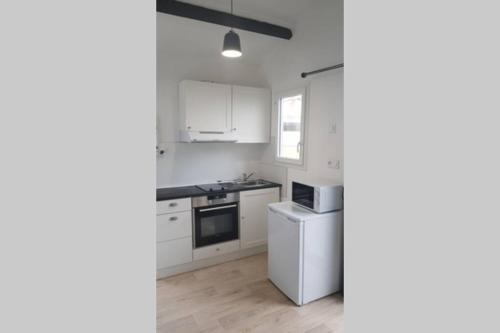 a kitchen with white cabinets and a stove top oven at Joli Studio tout équipé a votre disposition in Fleury-les-Aubrais