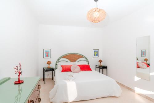 Dormitorio blanco con cama blanca y almohadas rojas en Villa Amura - Due Golfi, en SantʼAgata sui Due Golfi