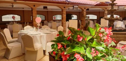 a dining room with white tables and chairs and flowers at Hotel Bulevard in Făgăraş