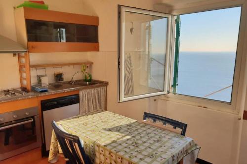 una pequeña cocina con mesa y ventana en Pace tra gli ulivi e il mare, en Sori