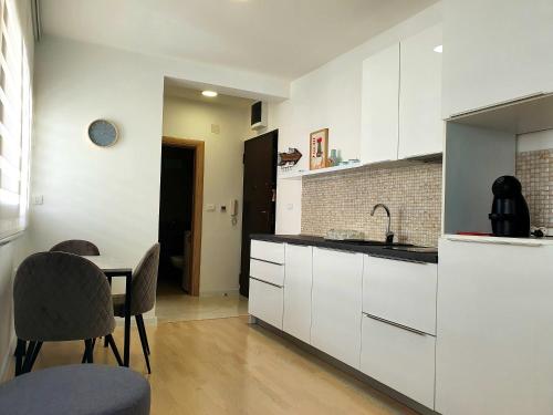 a kitchen with white cabinets and a table with chairs at Aleksandar First Sea Line Apartment in Bar
