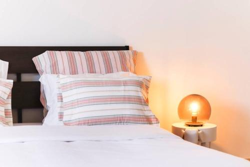 a bed with a pillow and a lamp on a table at CAPARICA BEACH VILLA in Trafaria