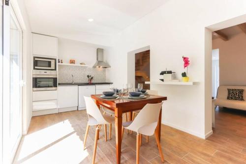 a kitchen and dining room with a wooden table and chairs at CAPARICA BEACH VILLA in Trafaria