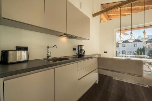 a kitchen with white cabinets and a sink and a window at latemar - schlosserhaus 31 in Tesimo