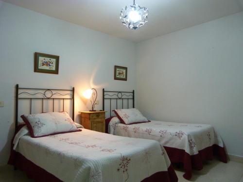 Casas del Parador - Las Eras في Villanueva del Conde: غرفة نوم بسريرين وثريا