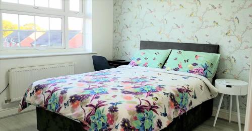 a bedroom with a bed with a floral bedspread at Relaxing En-suite Double Room in Derby