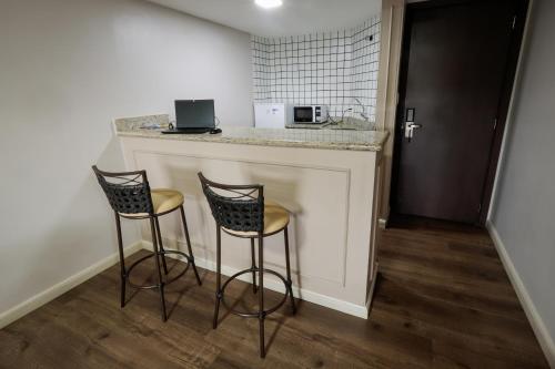 a kitchen with two bar stools and a counter at Hotel Pousada da Serra in Maracaju