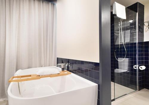 a bathroom with a white tub and a shower at Sudima Auckland City in Auckland