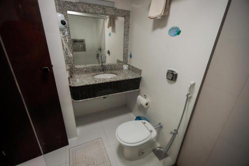 a bathroom with a toilet and a sink and a mirror at Hotel Pousada da Serra in Maracaju