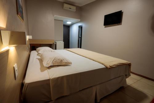 a bedroom with a bed and a tv on the wall at Hotel Pousada da Serra in Maracaju