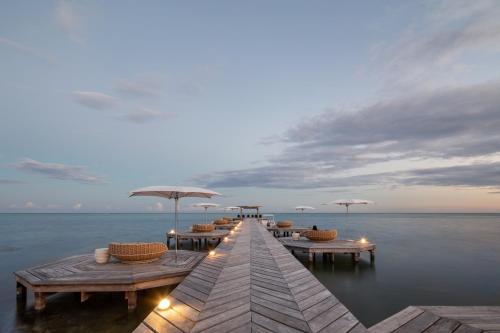 a pier with tables and umbrellas on the water at Matachica Beach Resort and Spa in San Pedro