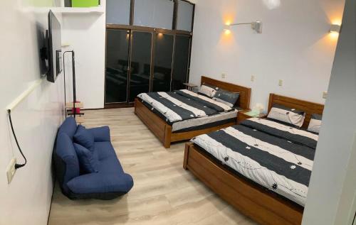 a bedroom with two beds and a blue chair at 瑞恒行館Reui Heng Guesthouse in Budai