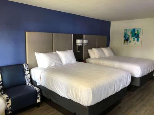 a hotel room with two beds and a chair at SureStay Plus Hotel by Best Western Sacramento Cal Expo in Sacramento