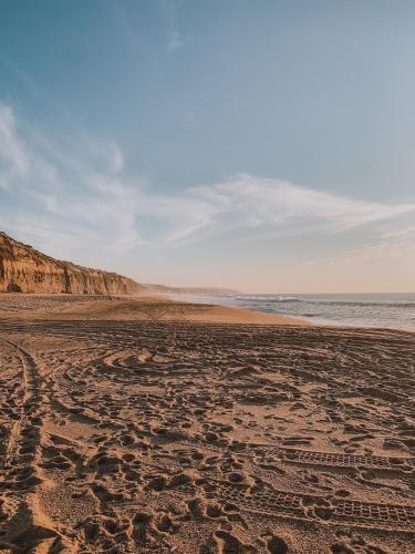 an empty beach with footprints in the sand at Casa das Laranjeiras in Alfarim