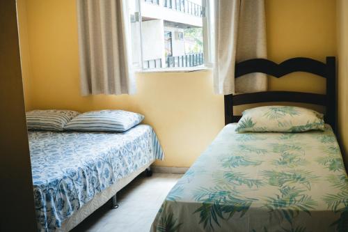 1 dormitorio con 2 camas y ventana en Aconchego na Passagem, en Cabo Frío