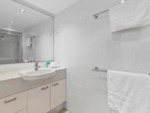 Un baño blanco con lavabo y espejo. en Picture Point Penthouse 11 - Private Rooftop Spa, en Noosa Heads
