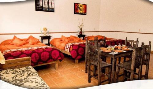 1 dormitorio con 2 camas, mesa y sillas en Posada Acaxiloco, en Cuetzalán del Progreso