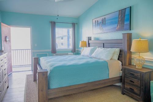 a blue bedroom with a bed and a window at Sea and Breeze Hotel and Condo in Tybee Island