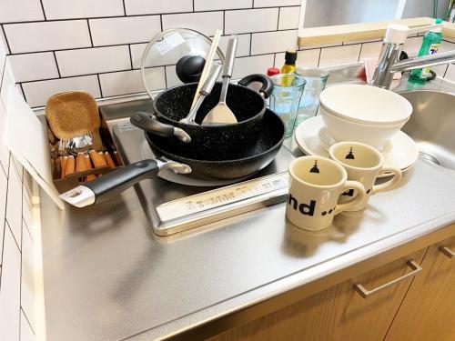 a kitchen counter with a sink with a pot and cups at @RLiS_house大阪ドームシティ in Osaka