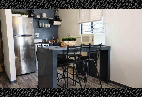 Il comprend une cuisine équipée d'un comptoir avec des chaises et d'un réfrigérateur. dans l'établissement The White Bungalow, à Rosarito
