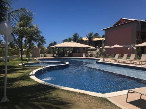 a swimming pool in a resort with chairs around it at Village Itacimirim, Pé na areia, Excelente 7B in Itacimirim