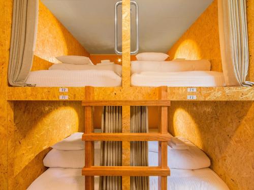 a room with three bunk beds in a cave at Seawall Hostel in Chatan