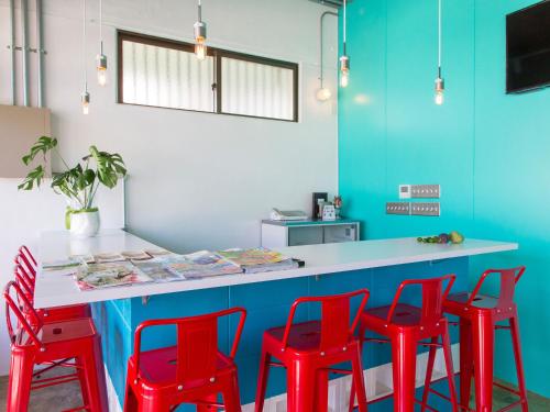 a kitchen with red chairs and a blue counter at Seawall Hostel in Chatan