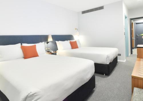 a hotel room with two beds and a desk at Sudima Auckland City in Auckland