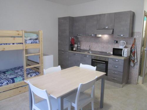 kuchnia ze stołem i krzesłami oraz łóżkiem piętrowym w obiekcie Appartamento in Toscana con Piscina e giardino w mieście Arpiola