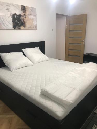 Una cama con sábanas blancas y almohadas en un dormitorio en Apartament Colina, en Cluj-Napoca