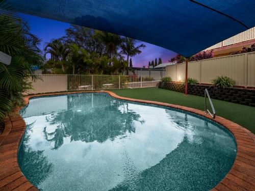 a swimming pool with a blue umbrella over it at Kennedy Drive Boutique Motel - Close To City Centre & Airport in Tweed Heads