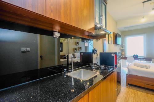 a kitchen with a sink and a bed in a room at Modern and Compact Studio at Patraland Urbano Apartment By Travelio in Bulanbulan