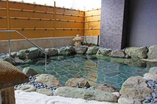 a hot tub in a yard with rocks and a fire hydrant at Sun Royal Hotel Kameoka Ekimae in Kameoka