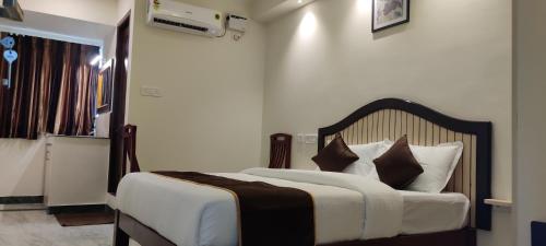 1 dormitorio con 1 cama con sábanas blancas y almohadas marrones en Rmc travellers inn, en Chennai