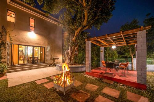 a patio with a fire pit in front of a house at Taruchaya by VEO - Part of StayVista in Raichak