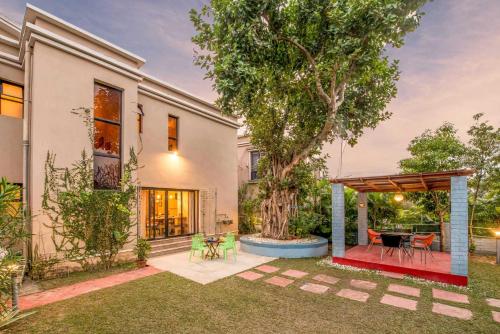 a backyard with a table and a tree at Taruchaya by VEO - Part of StayVista in Raichak