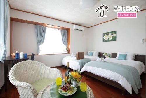 宮古島にある宮古島　ホワイトハウスのベッド2台、テーブルと椅子が備わるホテルルームです。