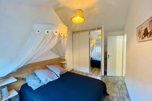 une chambre avec un lit bleu et un miroir dans l'établissement Les pignots Logement T2 Bassin Arcachon, à Gujan-Mestras