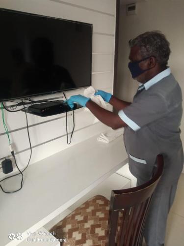 a man wearing a mask and gloves in front of a television at Miles Inn Hotel in Hassan