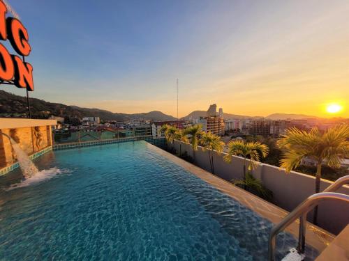 a swimming pool on the roof of a building with the sunset at Patong Mansion - SHA Certified in Patong Beach
