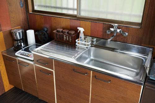 Una cocina con fregadero de acero inoxidable y gabinetes de madera. en Awaji Aquamarine Resort #1 BBQ OK! - Self Check-In Only, en Akashi