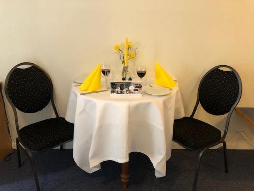 a table with two chairs and a white table with yellow folders at Purhus Kro in Fårup