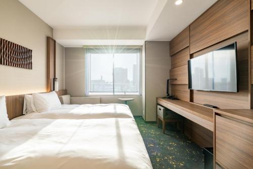 a hotel room with two beds and a flat screen tv at The Royal Park Canvas - Kobe Sannomiya in Kobe