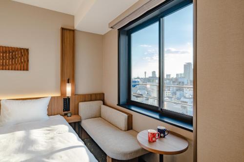 a hotel room with a bed and a chair and a window at The Royal Park Canvas - Kobe Sannomiya in Kobe
