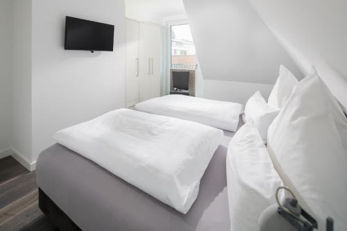 Dos camas en una habitación con sábanas blancas. en Haus Insulaner Tolle 8, en Norderney