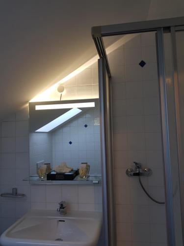 un baño con lavabo y una luz sobre un espejo. en Novitel Pension Pliening - München Messe, en Pliening