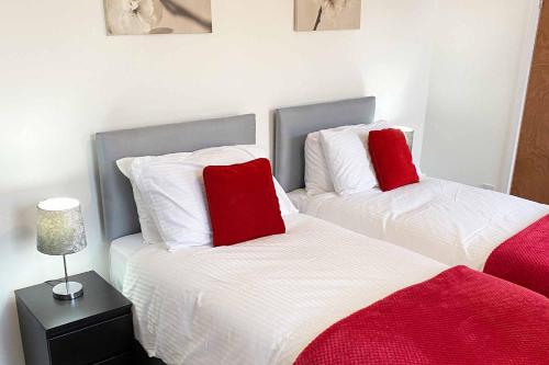 two beds with red pillows in a bedroom at Sutton Contractor Accommodation - Warrington, St Helens in Clock Face