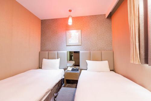 two beds in a room with orange walls at Shianghu Boutique Hotel in Chiayi City