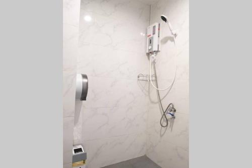 a shower in a bathroom with white marble walls at Khoksametchun Hostel Plus in Hat Yai
