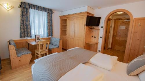 a bedroom with a bed and a desk and a table at Hotel Diamant Park in Campitello di Fassa